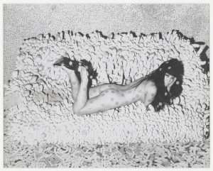 foto-van-collage-circa-1966-van-yayoi-kusama-met-de-kunstenaar-liggend-op-accumulation-no-2